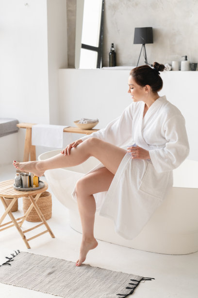 剃须后光滑皮肤的垂直照片。女性剃须后在腿部涂抹保湿霜。在家做Spa美容。身体的皮肤护理图片下载