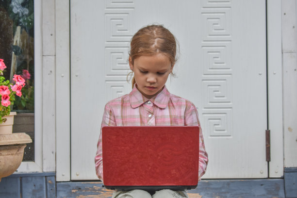 一个女孩带着笔记本电脑坐在房子的门廊上上课，在没有滤镜的远程照片上图片下载
