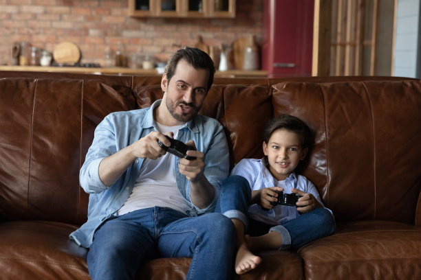 顽皮的年轻爸爸和十几岁的儿子玩电子游戏图片下载