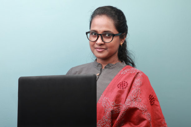 一名印度裔妇女带着微笑的表情用她的笔记本电脑工作图片下载