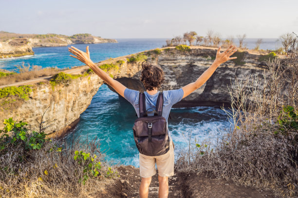 年轻男子在破碎海滩附近旅游在努沙Penida，印度尼西亚的天使比拉邦海滩。热门旅游胜地巴厘岛图片下载