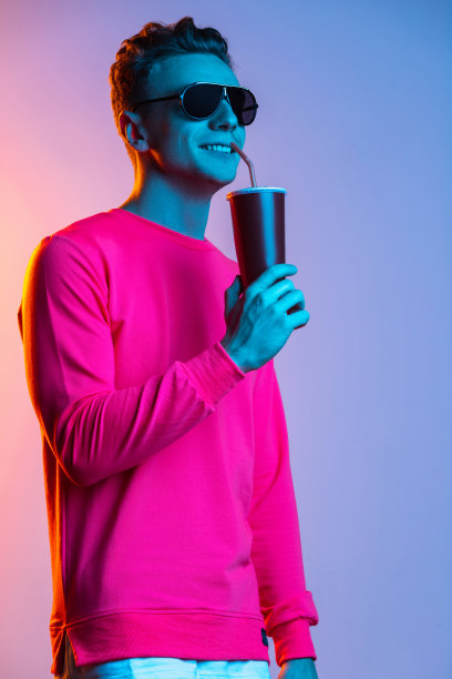 年轻时尚男人的肖像，与塑料玻璃孤立紫色工作室背景在粉红色霓虹灯滤光片。概念人类的情感，面部表情，青春，感情，广告。图片下载