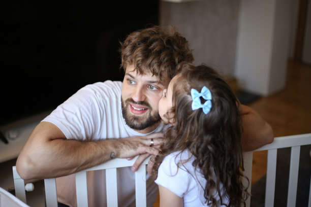 小女孩帮她爸爸组装婴儿床。库存图片图片下载