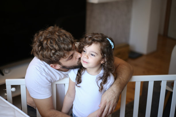 小女孩帮她爸爸组装婴儿床。库存图片图片下载