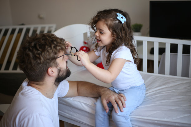 小女孩帮她爸爸组装婴儿床。库存图片图片下载