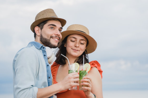 年轻的情侣在第一次约会喝鸡尾酒在酒吧餐厅与天空的背景-关注女孩的脸图片下载