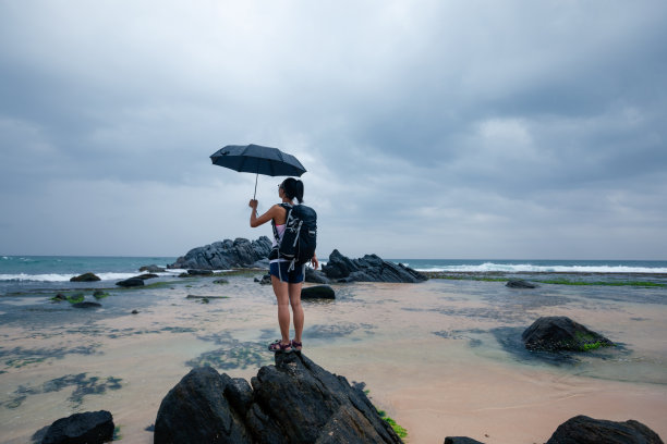 带着伞的女人在暴风雨中站在海边图片下载