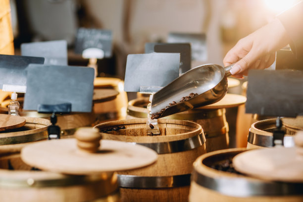 咖啡店女店员手拿装满咖啡豆的金属勺图片下载