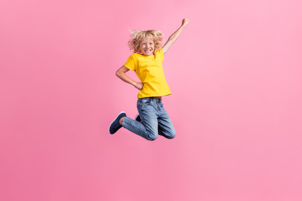 小男孩的全身照片快乐积极的微笑跳起来飞超级英雄的力量孤立在粉红色的背景图片下载
