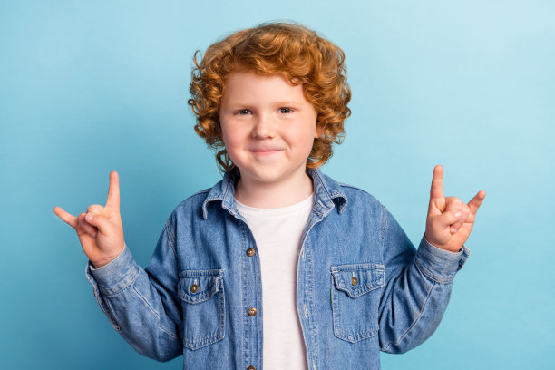 照片中的摇滚迷小姜男孩秀角象征穿着牛仔夹克孤立蓝色背景图片下载