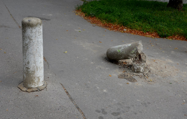 货车，车撞到了一根混凝土柱子上。柱子排成一列，将步行区和道路分开。皮肤弯曲了，加固线也损坏了。图片下载