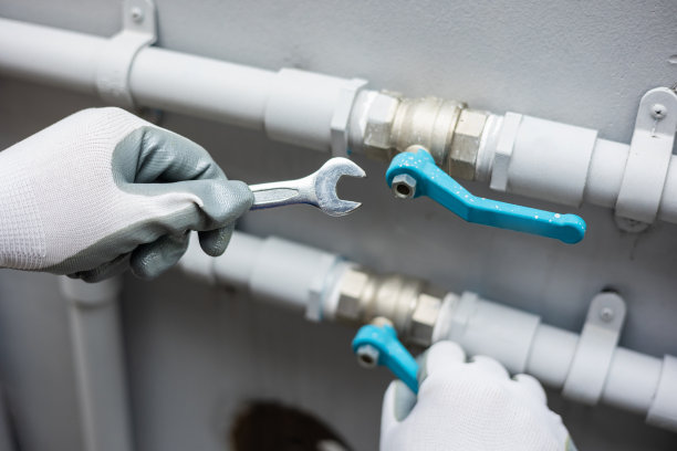 男管道工安装管道系统用扳手带水龙头。管道检查和维修服务。图片下载