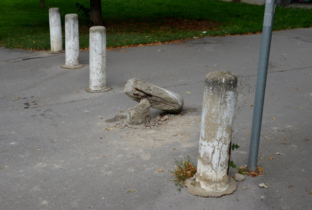 货车，车撞到了一根混凝土柱子上。柱子排成一列，将步行区和道路分开。皮肤弯曲了，加固线也损坏了。图片下载