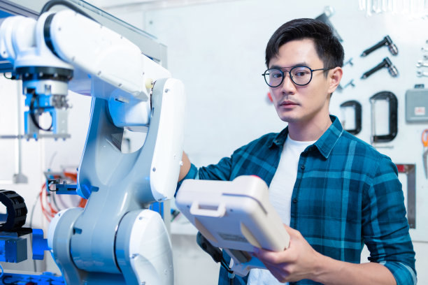 亚洲男性工程师在实验室维护机器手臂。他在一个拥有现代化设备的高科技研究实验室。科技与创新概念…图片下载