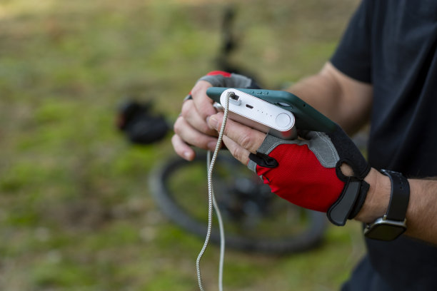 一名男子在森林里以一辆自行车为背景，用手机充电。图片下载