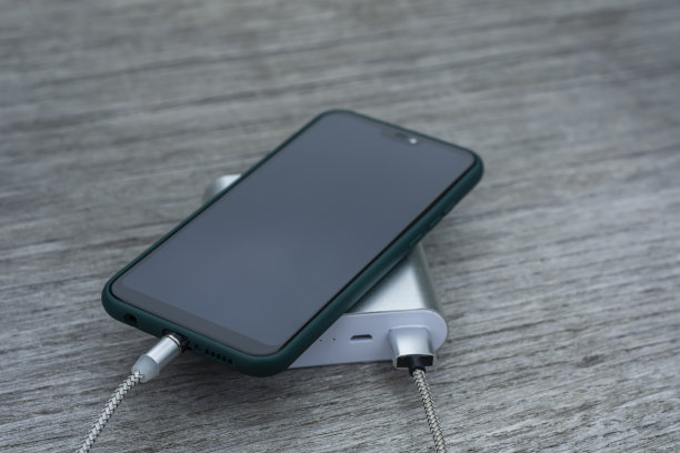 在公园的木凳上为智能手机充电。图片下载