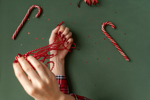 圣诞修指甲。红色指甲在绿色背景上。图片下载