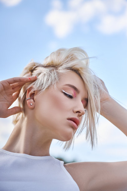 完美的红指甲修指甲的金发女人短发。在一个阳光明媚的夏日，一名女子在大自然中摆姿势图片下载