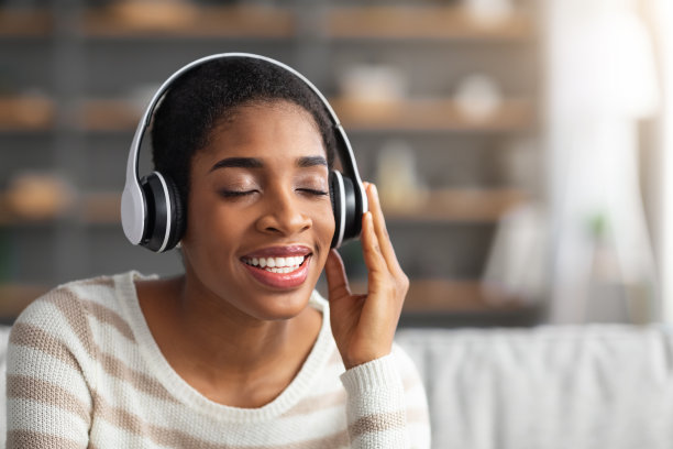 美丽的黑人女性在家里戴着无线耳机听音乐的肖像图片下载