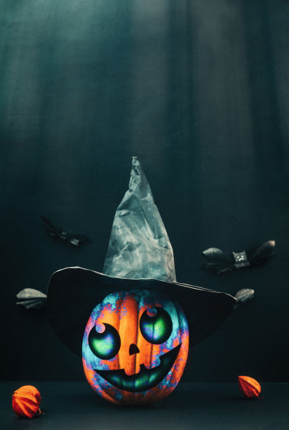 万圣节。一个装饰南瓜形状的杰克的灯笼在一个黑色女巫的帽子，酸浆和蝙蝠在黑暗的背景纸。垂直的。本空间图片下载