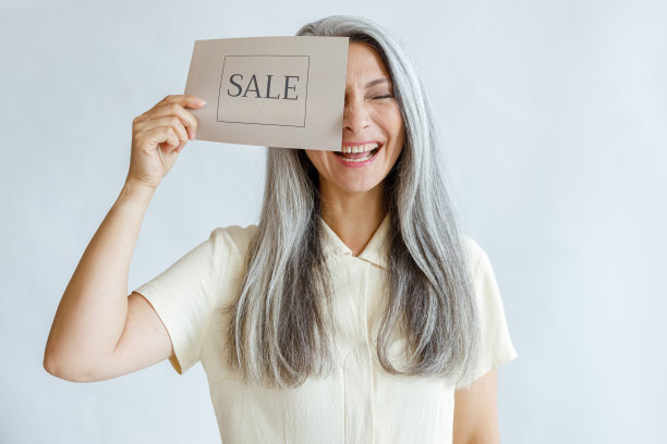 一个满头白发的中年女人在画室里挂着出售的牌子，笑着遮住眼睛图片下载