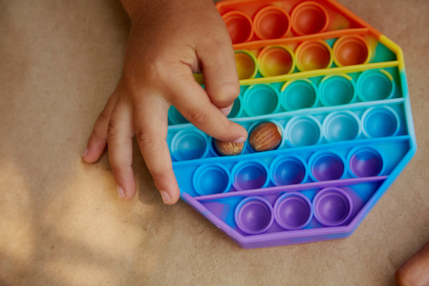 幼儿玩的pop it玩具和榛子。运动技能发展的游戏。彩虹触摸感官的烦躁。前视图。高质量的照片图片下载