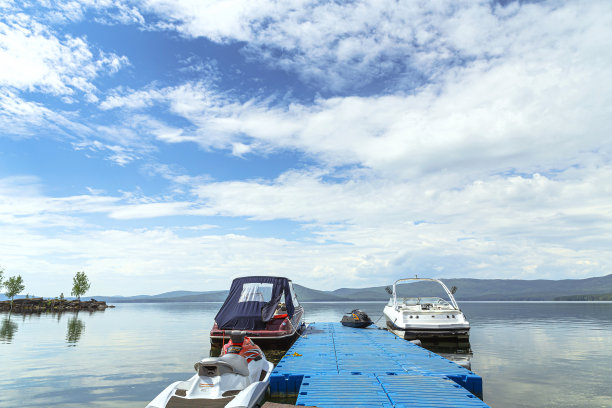 在蓝蓝的天空和群山的背景下，湖上码头附近的船只图片下载