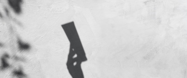 灰色的墙上，化妆品的影子和一只女性优雅的手。抽象，混凝土背景与一管奶油和树叶的反射。带有复制空间的横幅。图片下载