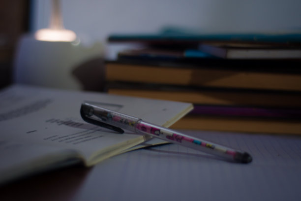 书房桌上有一堆书和一支笔，桌上有一盏台灯图片下载