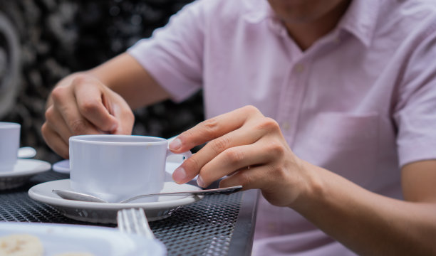 一名男子在户外端着一杯白色的热饮。图片下载