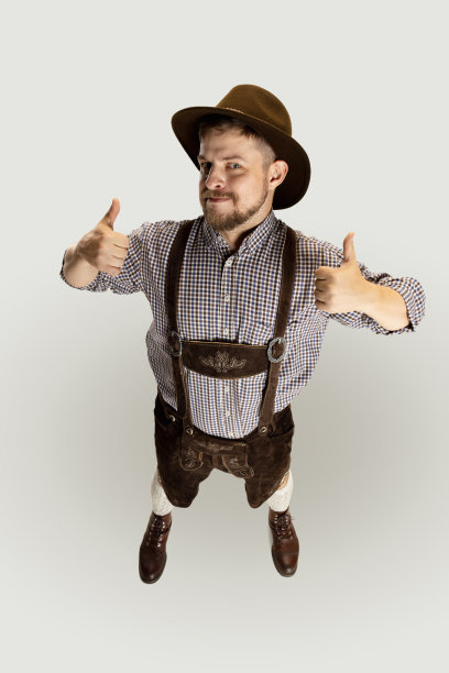 可爱的大胡子男人，身着传统奥地利或巴伐利亚服装的服务员，独自站在灰色的背景下。有趣的meme的情绪图片下载