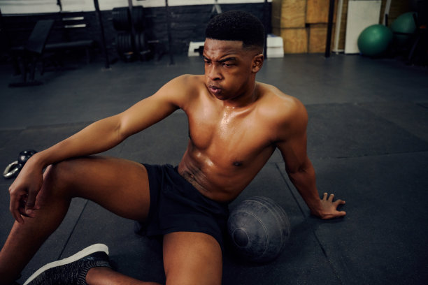 非裔美国男性，在激烈的健身运动后，在健身房地板上休息。男运动员在锻炼后看起来很疲惫。高质量的照片图片下载