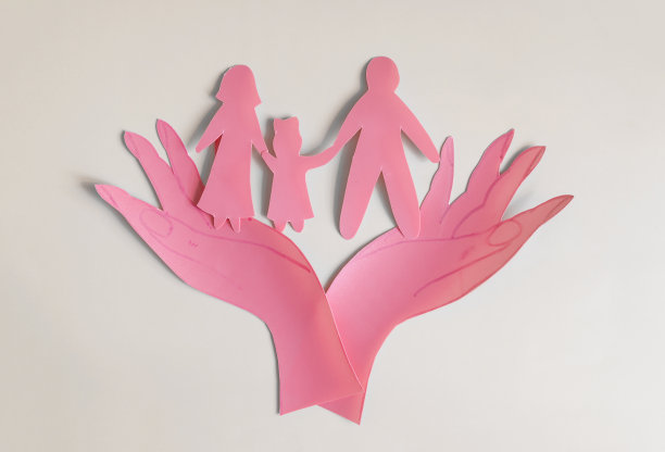 用红纸做的手托着两个大人和一个小孩的彩色背景。家庭关系的概念成人和受保护的儿童图片下载