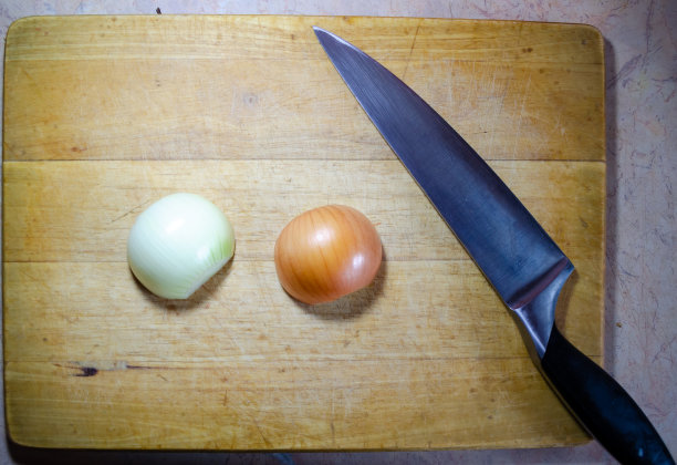 在木制砧板上用刀切两个半洋葱图片下载