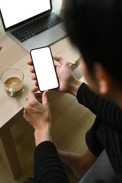 一名男子坐在沙发上用手机。图片下载