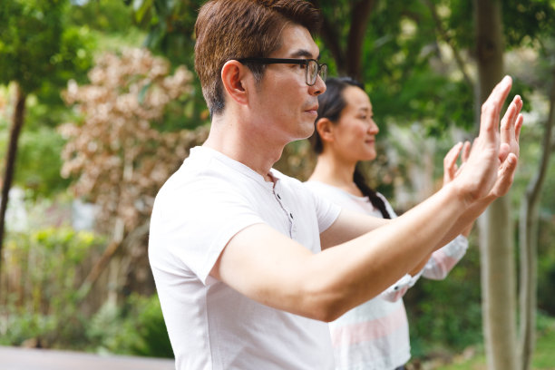 亚洲夫妇穿着白衬衫在户外锻炼，练太极图片下载