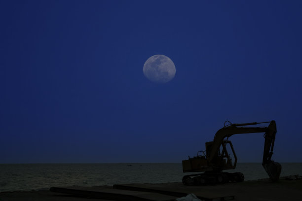 黄昏时分，大海背景上挖掘机的剪影图片下载