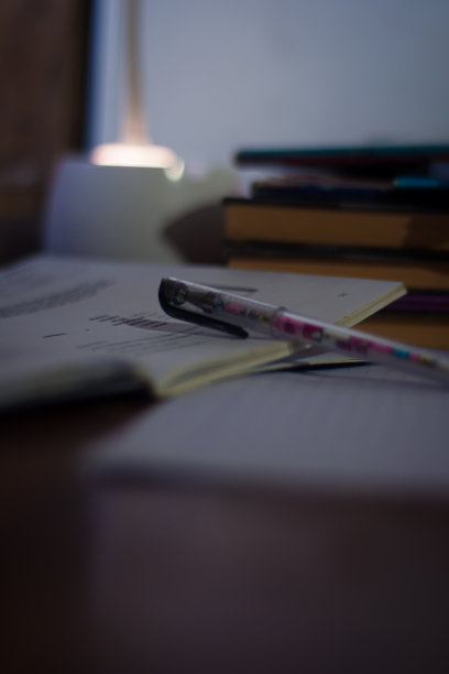 书房桌上有一堆书和一支笔，桌上有一盏台灯图片下载