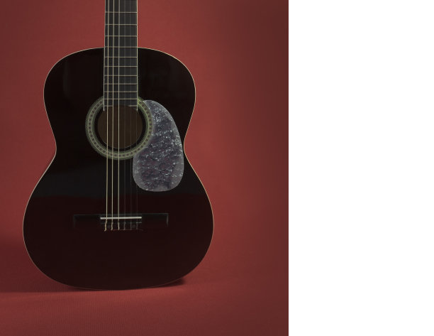 红色背景下的黑色原声吉他。卡。本空间图片下载