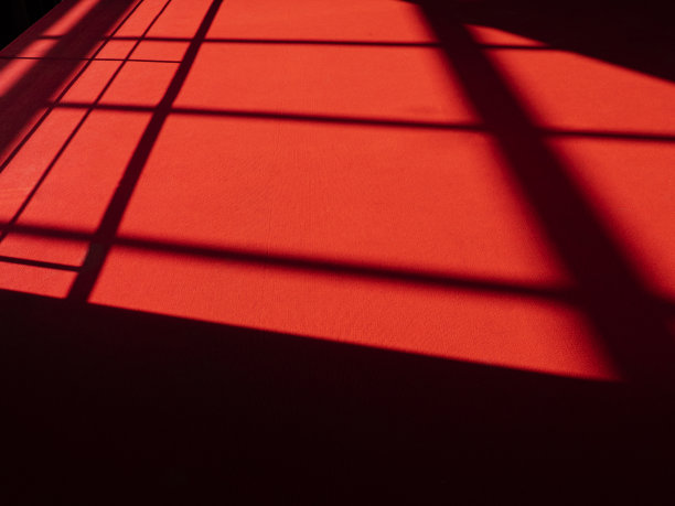 表面有抽象线条的红地毯，阳光在红地毯上，剪影和阴影在地板上图片下载