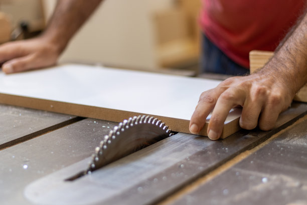 木工工人正在车间用工业电动木工切割机切割木材，用于家具制作图片下载
