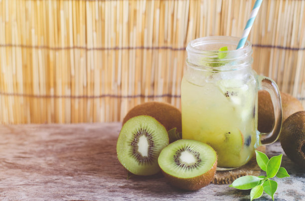 一组新鲜的切片猕猴桃和果汁放在玻璃罐中，以柔和的浅色调为背景图片下载