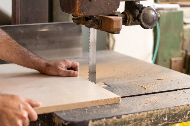 木工工人正在车间用工业电动木工切割机切割木材，用于家具制作图片下载