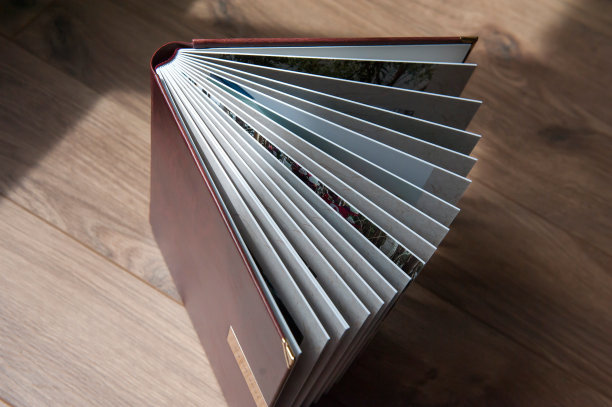 打开棕色的照片簿与厚精装塑料片对着木桌，特写。从上面的观点图片下载