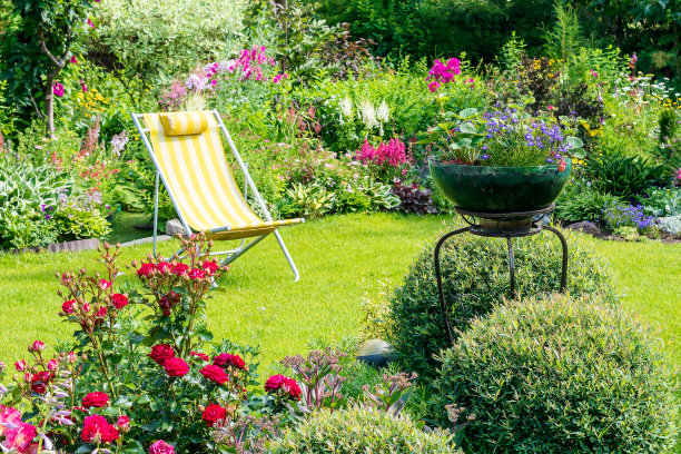 花园区域的一部分有美丽的多年生植物，绿色的草坪和阳光躺椅放松。图片下载
