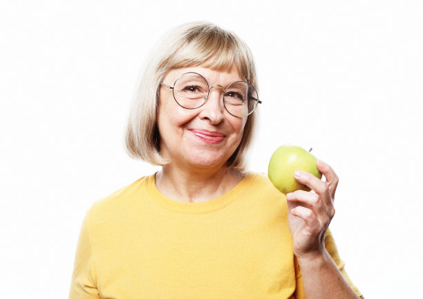 一位戴着眼镜，手持苹果的美丽老妇人的肖像图片下载