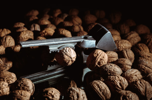胡桃夹子里的胡桃。黑暗的背景。美丽的背景和食物。健康的成分。有用的营养素。美味的饮食小吃。宏。棕色螺母。艺术照片。简而言之工具。壁纸图片下载