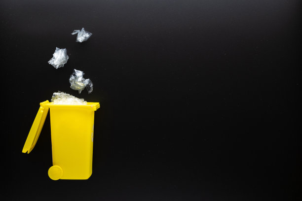 回收塑料排序。垃圾箱容器用于处理垃圾废物，节约环境。黑色背景上用于回收塑料垃圾的黄色垃圾桶。平的。图片下载