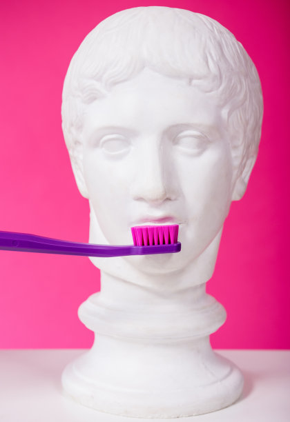 一名女牙医正在用一把大牙刷给一尊古玩雕像刷牙图片下载