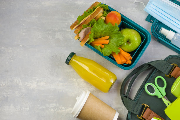 社会距离，学习和家庭教育。午餐盒，学校和办公用品，医用口罩在浅色背景下。回到学校的概念。保持安全。前视图。本空间图片下载